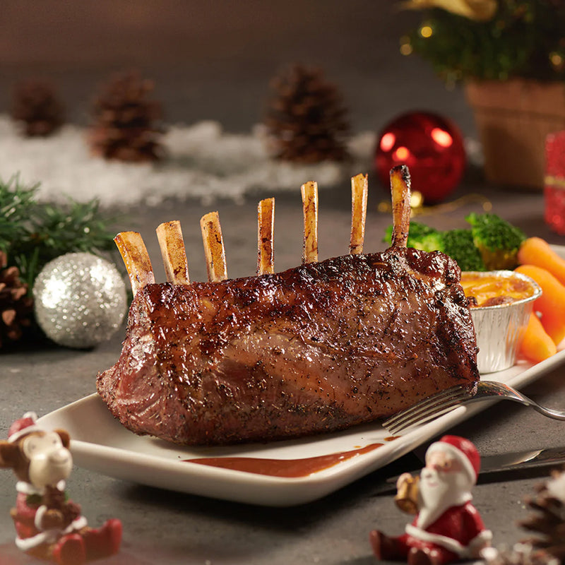 Grilled rack of lamb on a plate with festive decorations in the background