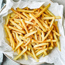 French fries in a bowl lined with parchment paper on a textured surface