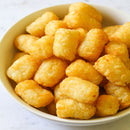 White bowl filled with golden tater tots on a light background