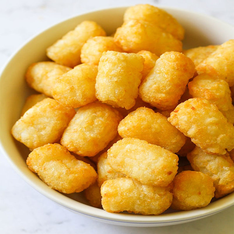 White bowl filled with golden tater tots on a light background