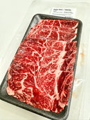 Raw marbled beef on a black tray with a label in the background