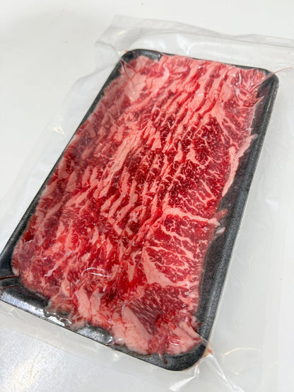Marbled red meat on a black tray with a white background