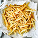 French fries in a bowl lined with parchment paper on a textured surface