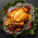 Roasted turkey on a decorative silver platter with greenery and berries