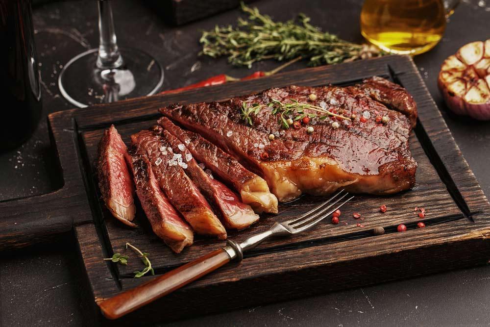 Pan-seared grass-fed striploin steak sliced to show medium-rare doneness